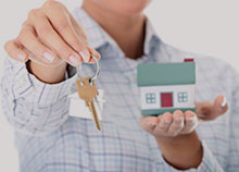 A man holding a toy house and holding out a set of keys